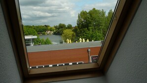 Un tragaluz con vistas a un lago, árboles y un edificio con un letrero que dice "Jadem".