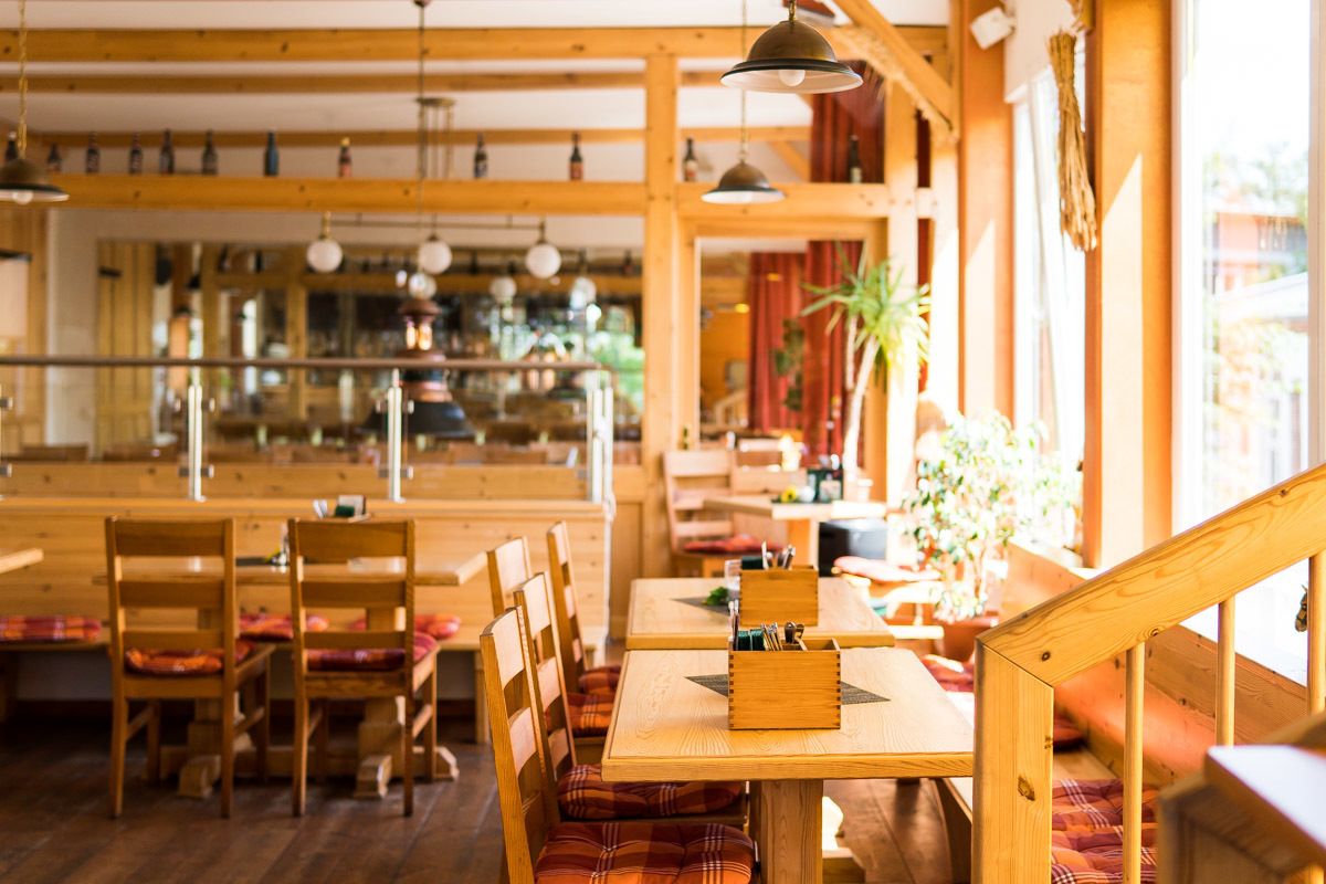 A restaurant with wooden furniture, pendant lighting, and a view of the street.
