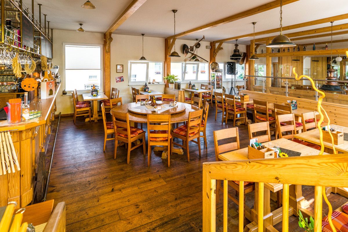 Een rustiek interieur met houten meubels, een bar en grote ramen voor natuurlijk licht.