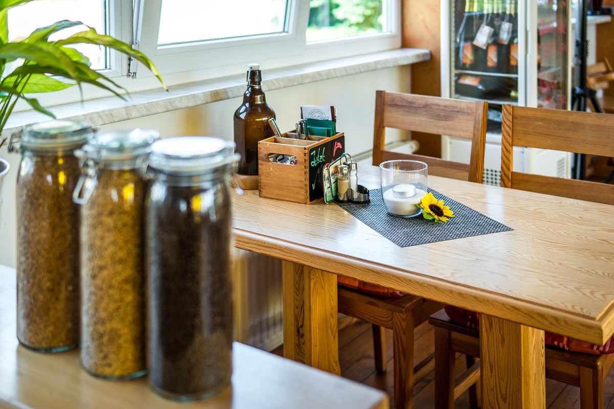 A wooden dining table with glass jars, a candle, and a small box with a chalkboard sign.