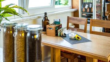 A wooden dining table with glass jars, a candle, and a small box with a chalkboard sign.