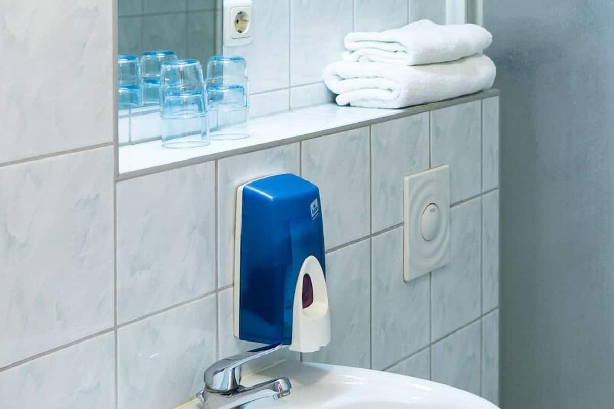 Une salle de bain avec un lavabo blanc, un miroir et une cabine de douche en verre.