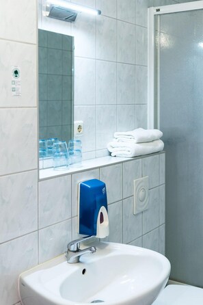 Un baño con un lavamanos blanco, un espejo y una cabina de ducha de vidrio.