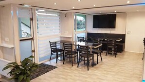 Uma área de jantar moderna com uma mesa grande e cadeiras, uma TV de tela plana na parede e vista pela porta de vidro.