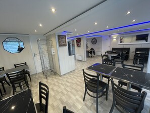 Welcome to our dining area, where guests can enjoy meals in a beautifully designed space with a central reception desk, dining tables, and a decorative wall piece.