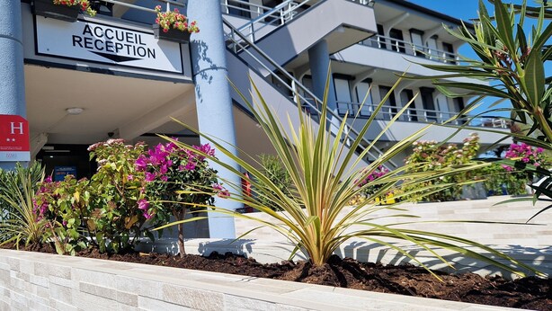 Uma área de recepção de hotel com uma placa que diz 'ACCUEIL RECEPTION' e o símbolo de acessibilidade para cadeiras de rodas.