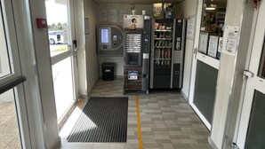 Um interior limpo e moderno, com máquina de vendas automática, máquina de café e frigorífico.
