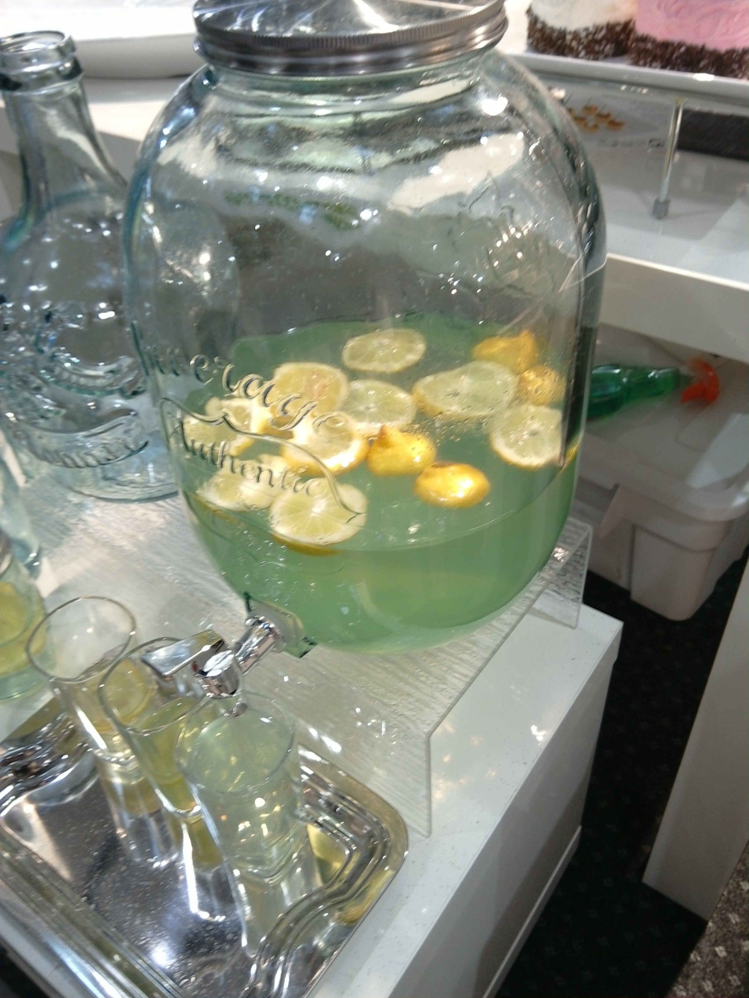 A glass jar with a metal lid containing a green liquid and lemon slices.