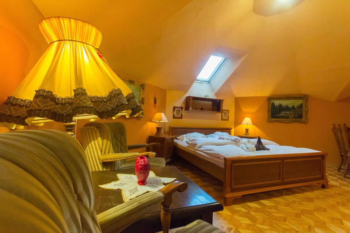 A cozy room with a bed, a chair, a table with a decorative item, and a lamp.