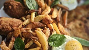 Un piatto con pollo fritto, patatine fritte, un uovo fritto e una fetta di pane.
