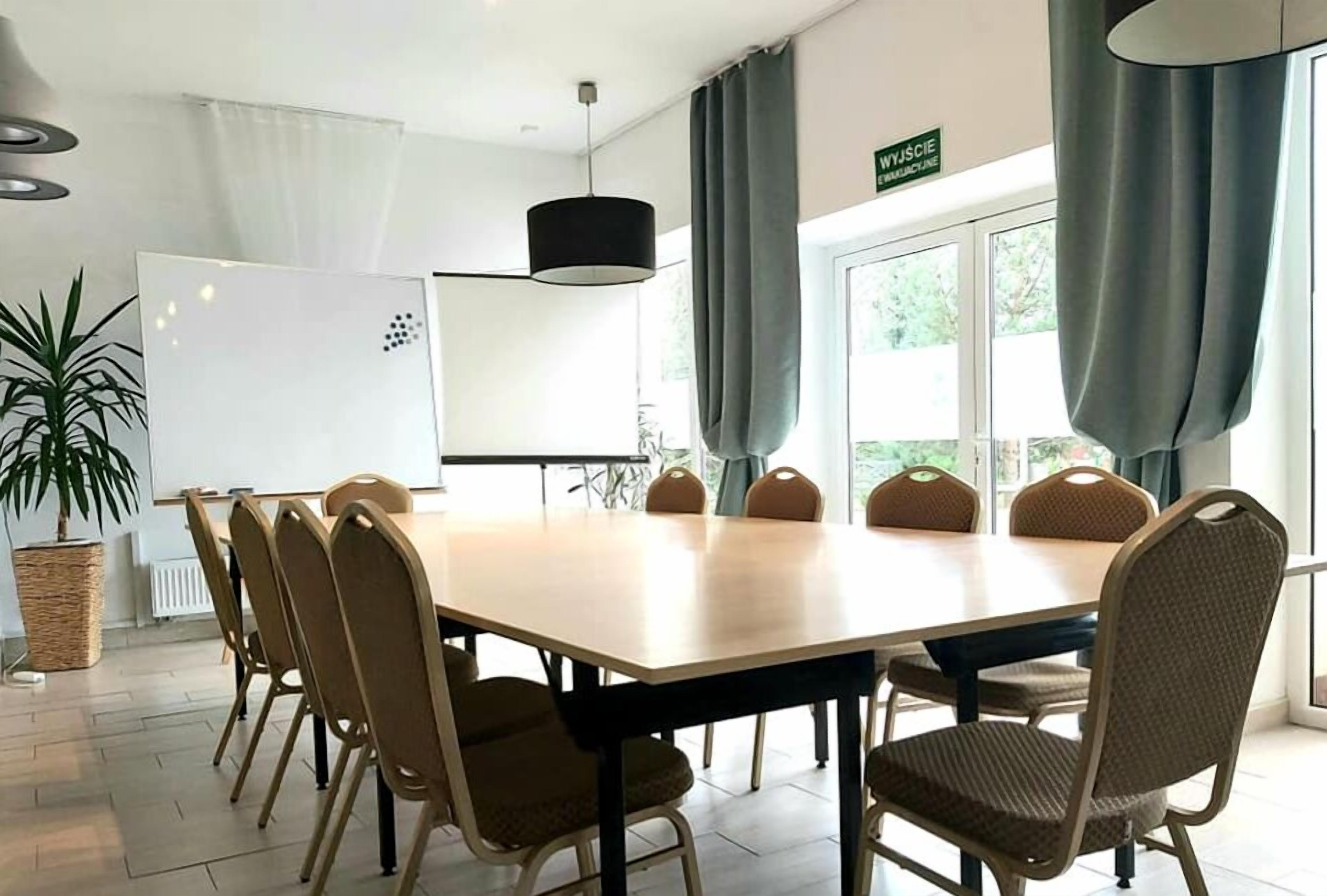 A conference room with a large table, chairs, a whiteboard, and a sign indicating a workout area.