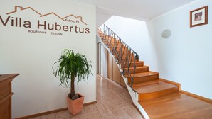 Un interior moderno con una escalera, una planta en maceta y un letrero en la pared que dice Villa Hubertus Boutique Design.