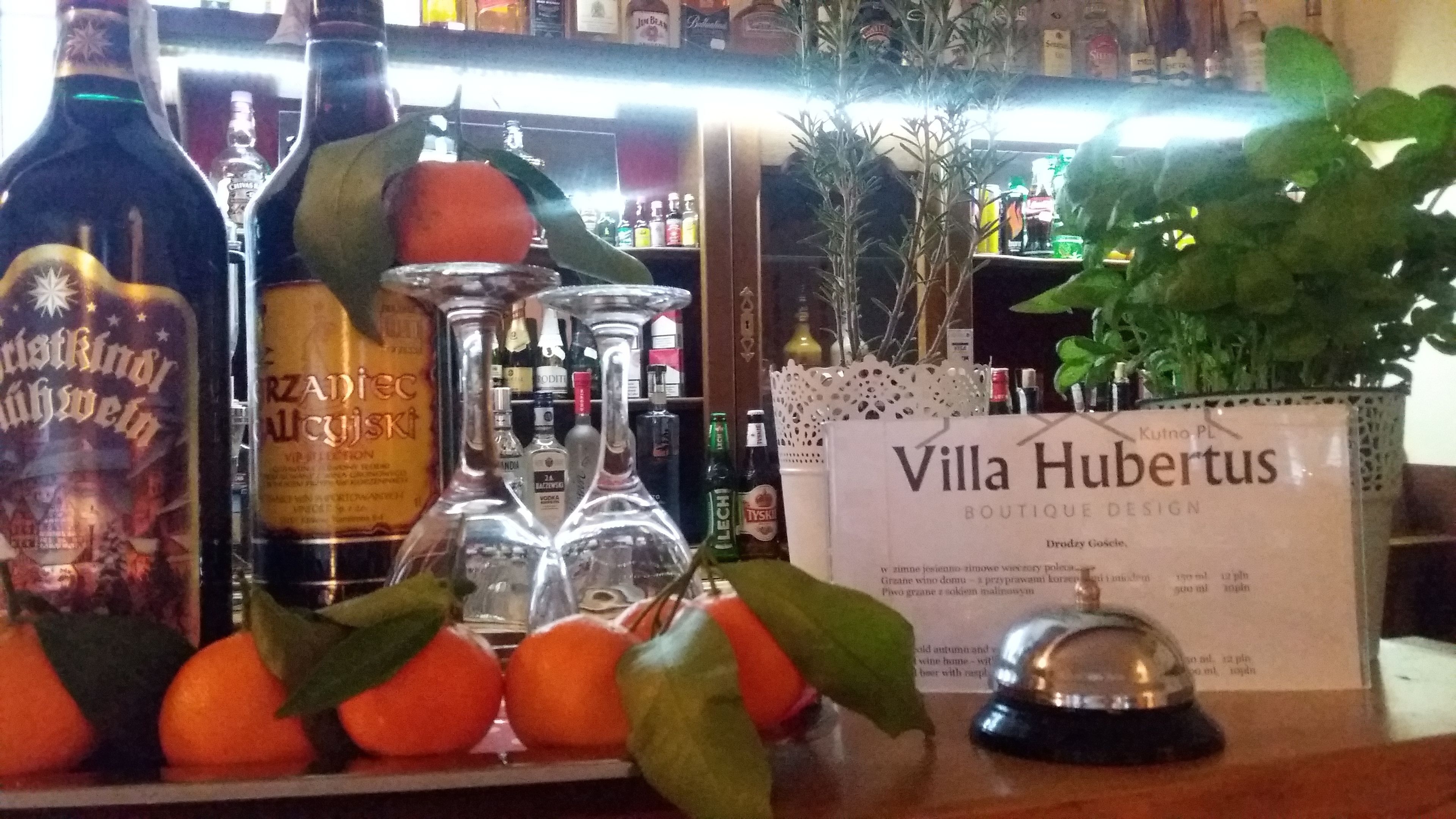A bar area with bottles, glasses, and a sign for Villa Hubertus.