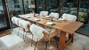 A dining table set for six with white chairs, a wooden table, and a view of greenery outside. - The Dunstane - No 4 (Edinburgh)