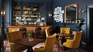 A bar area with a wooden counter, multiple bar stools, and a large mirror on the wall. - The Dunstane - No 4 (Edinburgh)