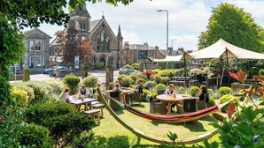 A courtyard with outdoor seating, a hammock, and a historic building in the background. - The Dunstane - No 4 (Edinburgh)