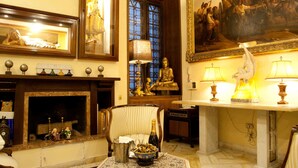 A room with a fireplace, a Buddha statue, a painting, and a table with a bottle and bowl. - Guesthouse Borromeo Roma (Rome)