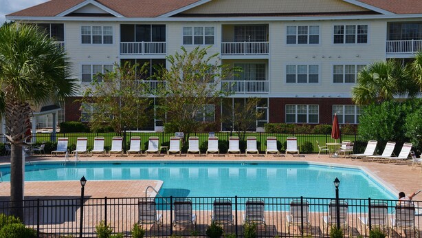A hotel with a swimming pool, multiple balconies, and outdoor seating areas. - 1023 The Havens (North Myrtle Beach)