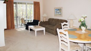 Een woonkamer met een bank, een salontafel, een eettafel met stoelen en een schilderij aan de muur.