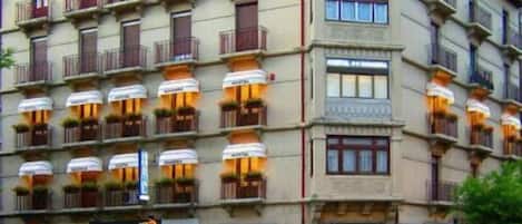 A multi-story hotel with balconies, a bar, and various shops on the ground floor.
