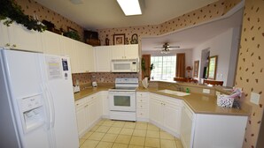 A kitchen with white cabinets, a microwave, an oven, a sink, and a ceiling fan. - 123 Harbour Cove (North Myrtle Beach)