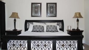 Un dormitorio con una cama, dos lámparas de noche y dos cuadros enmarcados en la pared.