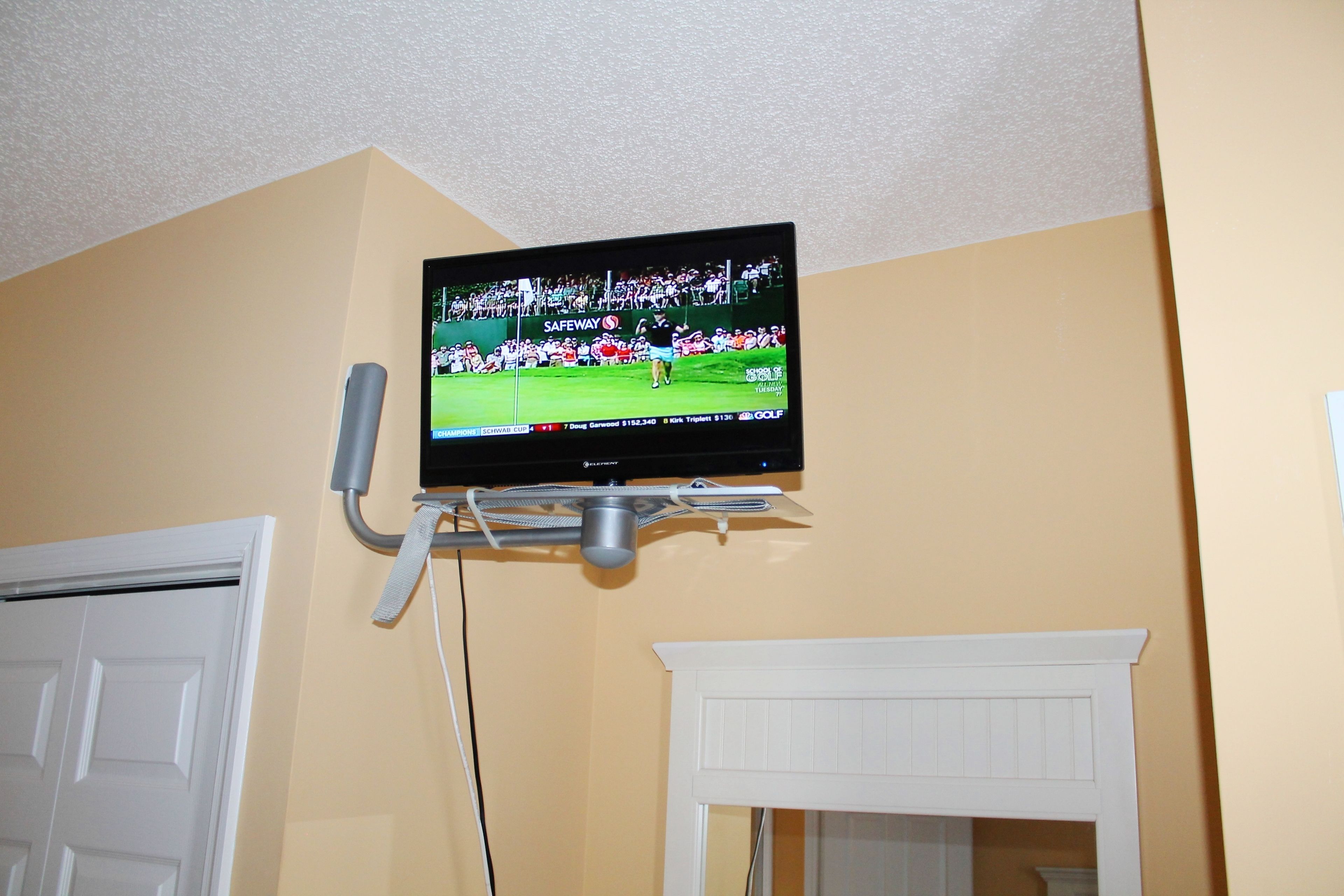 A television mounted on a wall in a room with a white door and a white fireplace.
