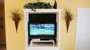 En tv-apparat står på en vit tv-bänk, och på var sin sida om den finns två dekorativa blomkrukor.