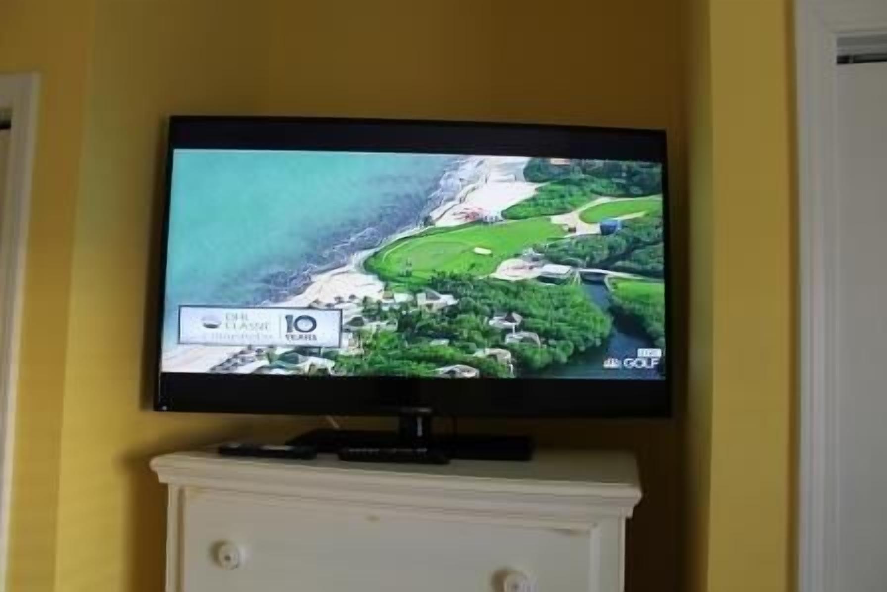 A television displaying a golf course with a view of the ocean.