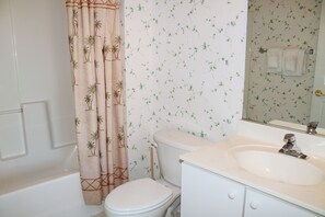 A bathroom with a toilet, sink, and shower curtain. - 1024 Cypress Bend (North Myrtle Beach)