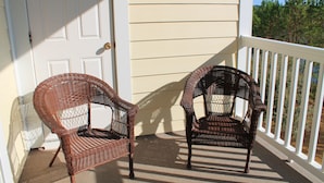 Two wicker chairs on a porch with a white door and railing. - 1534 Willow Bend (North Myrtle Beach)
