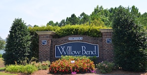 A brick sign with "Willow Bend" written on it, surrounded by greenery and a flower bed. - 1534 Willow Bend (North Myrtle Beach)