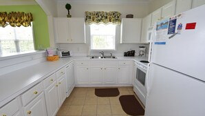Une cuisine avec des meubles blancs, un évier, une cuisinière et un réfrigérateur.