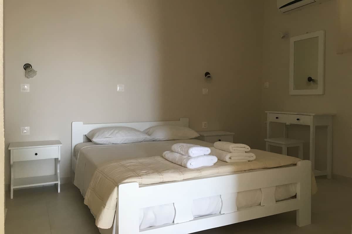 Un dormitorio con cama, mesitas de noche, cómoda, aire acondicionado y espejo.
