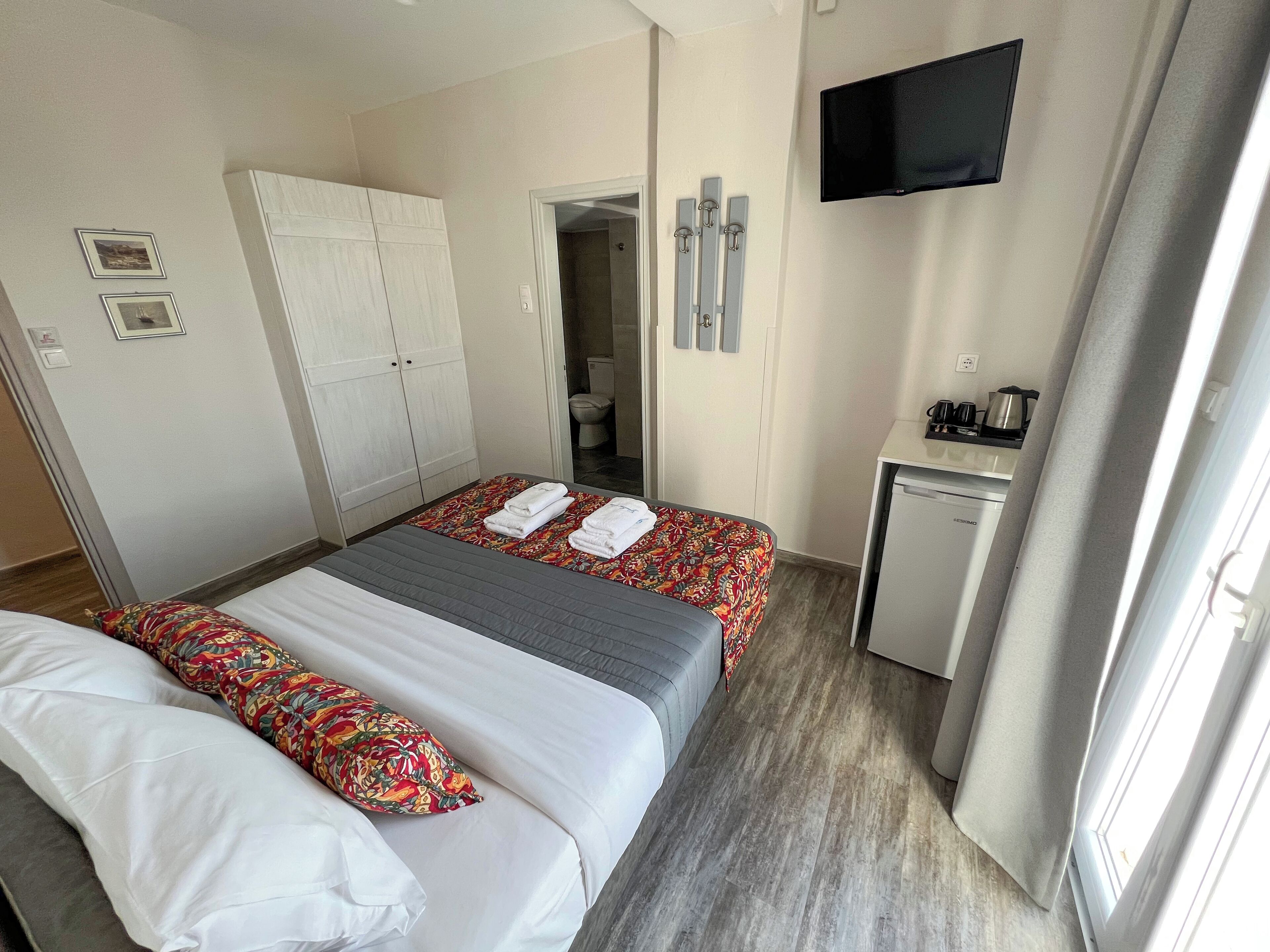 A hotel room with a bed, a desk, a television, and a wardrobe.