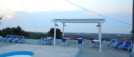 A rooftop terrace with a swimming pool, outdoor seating, and a view of the landscape.