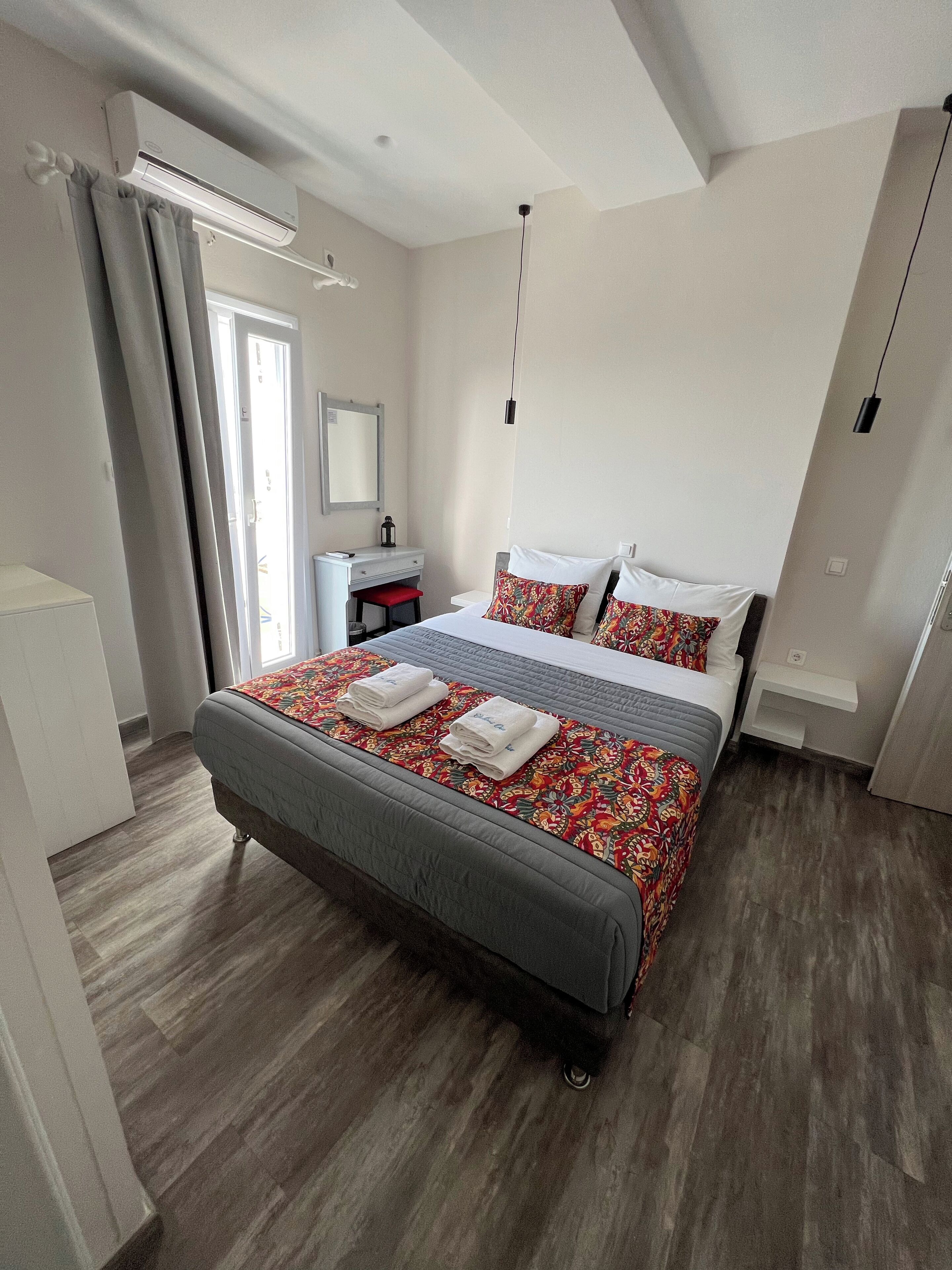 A modern bedroom with a large bed, a bedside table, a mirror, and a wardrobe.