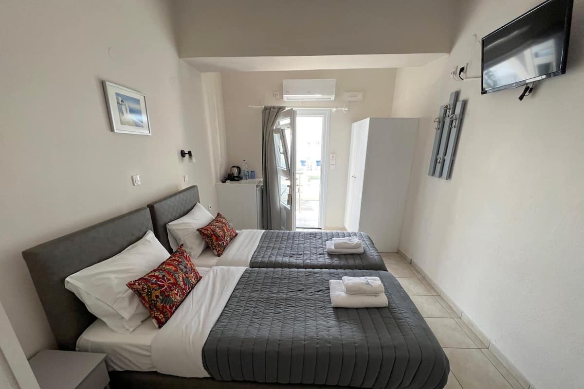 Habitación de hotel con dos camas, televisión y vista al exterior.