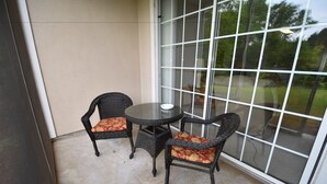 A glass-enclosed patio with wicker furniture and a round table.