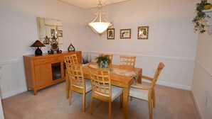 A dining room with a wooden table, chairs, a chandelier, a cabinet, and framed pictures on the wall.