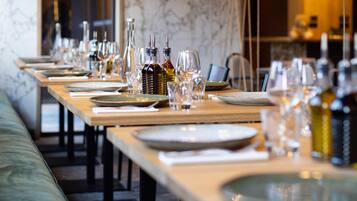 A long dining table set with plates, glasses, and bottles, likely in a restaurant or dining area.