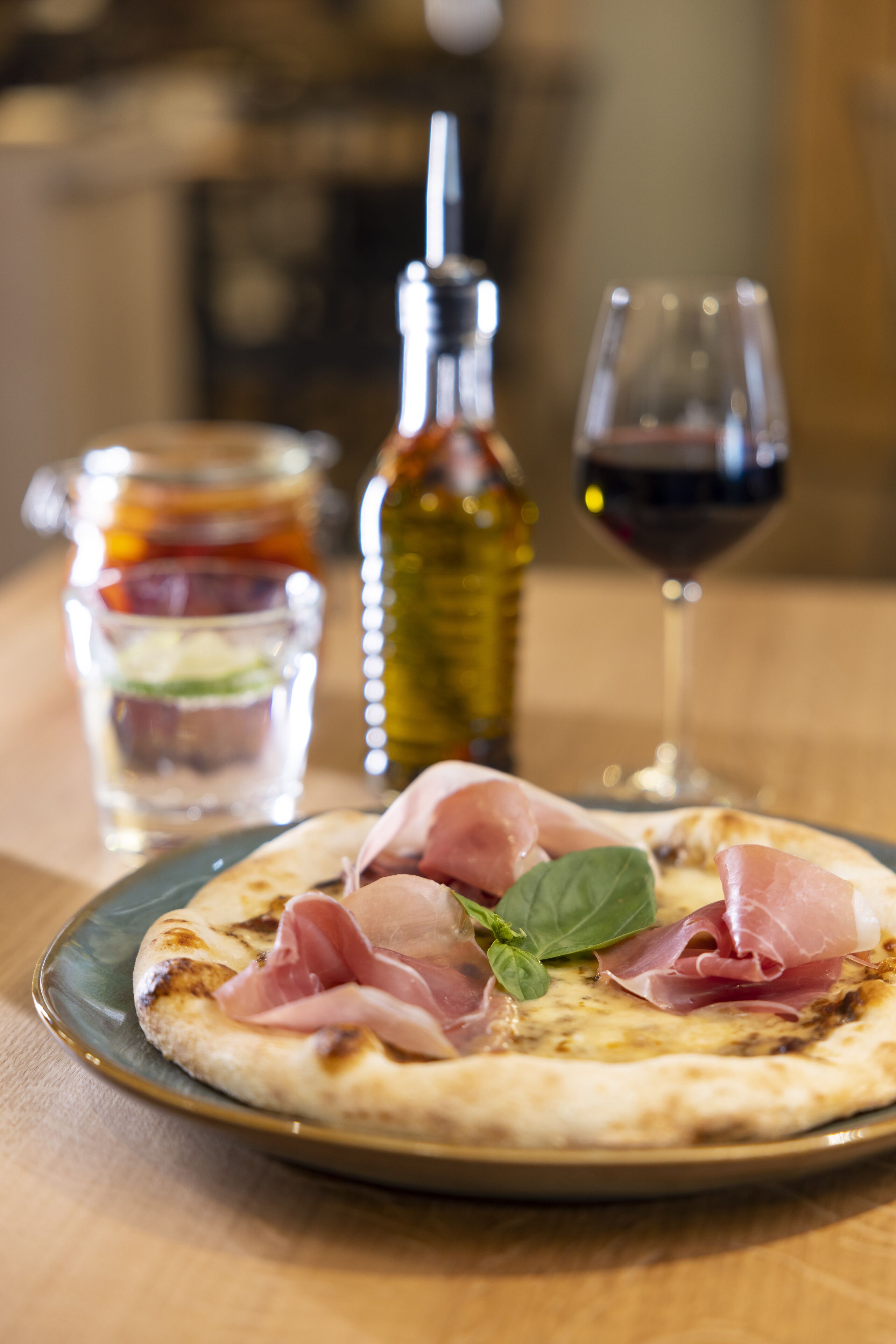 Eine Pizza mit Schinken und Basilikum auf einem Holztisch.