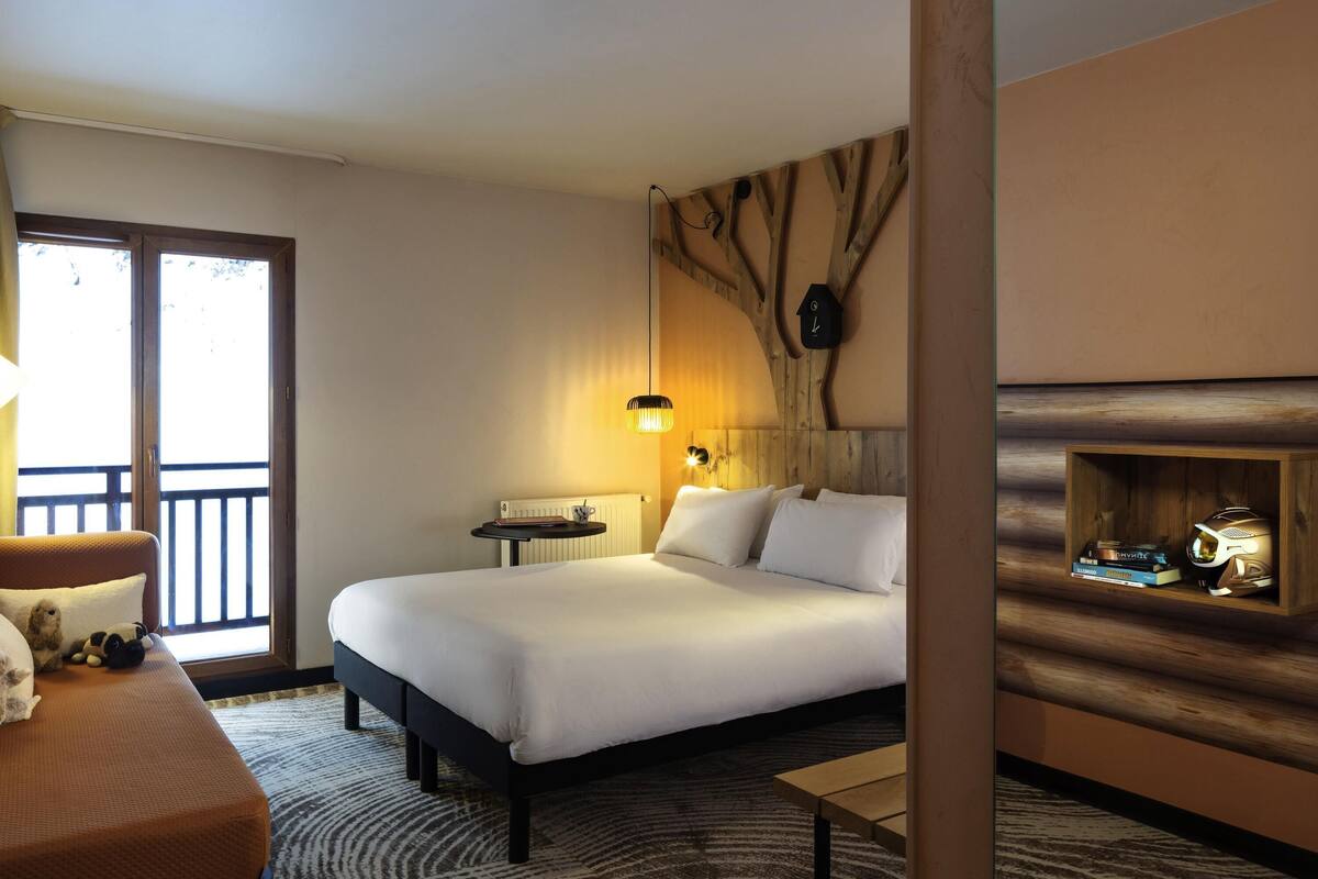 Une chambre d’hôtel avec un grand lit, une petite table, un canapé et une vue sur l’extérieur.
