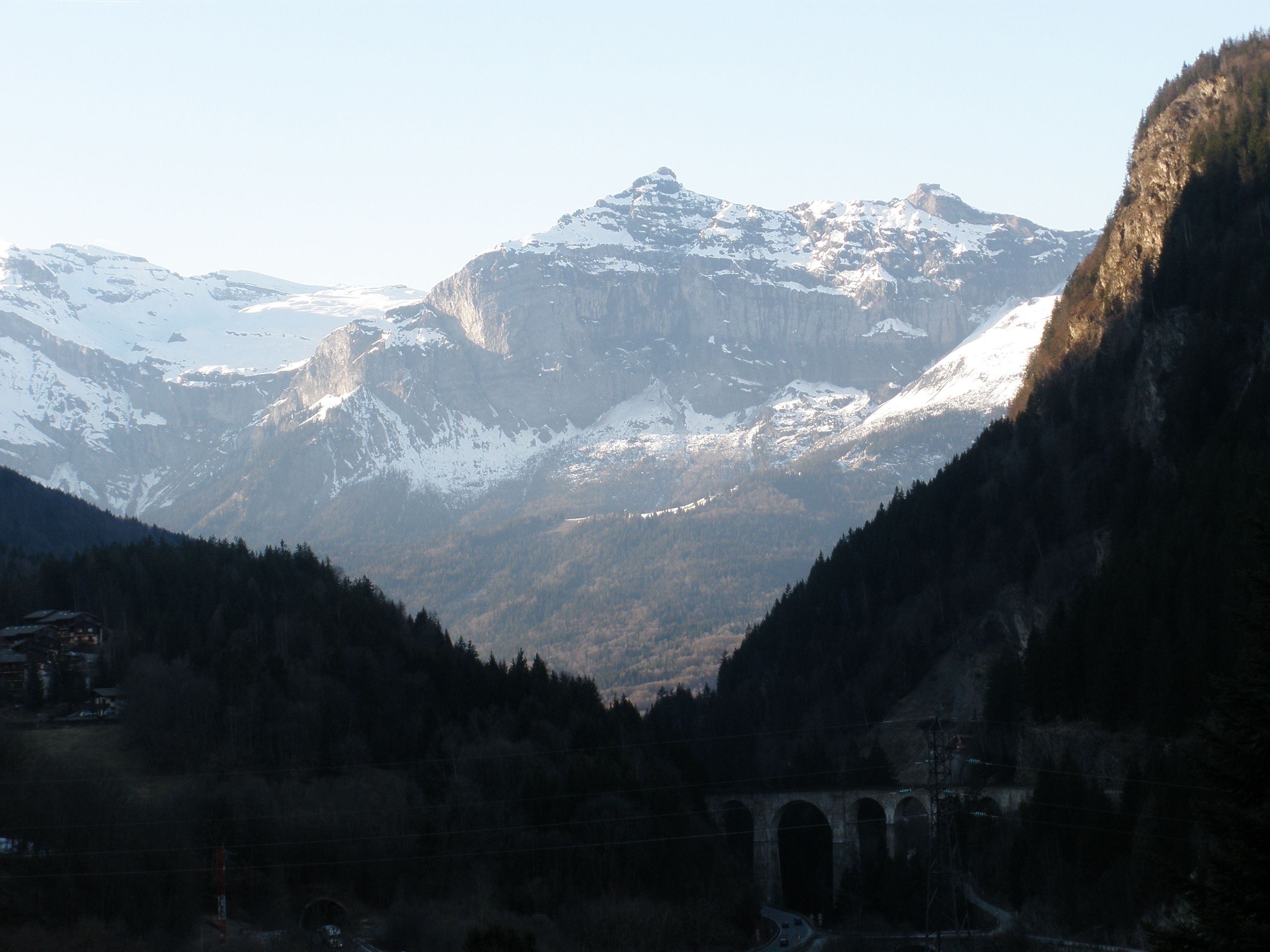 A mountain landscape with a bridge and a building in the foreground.
