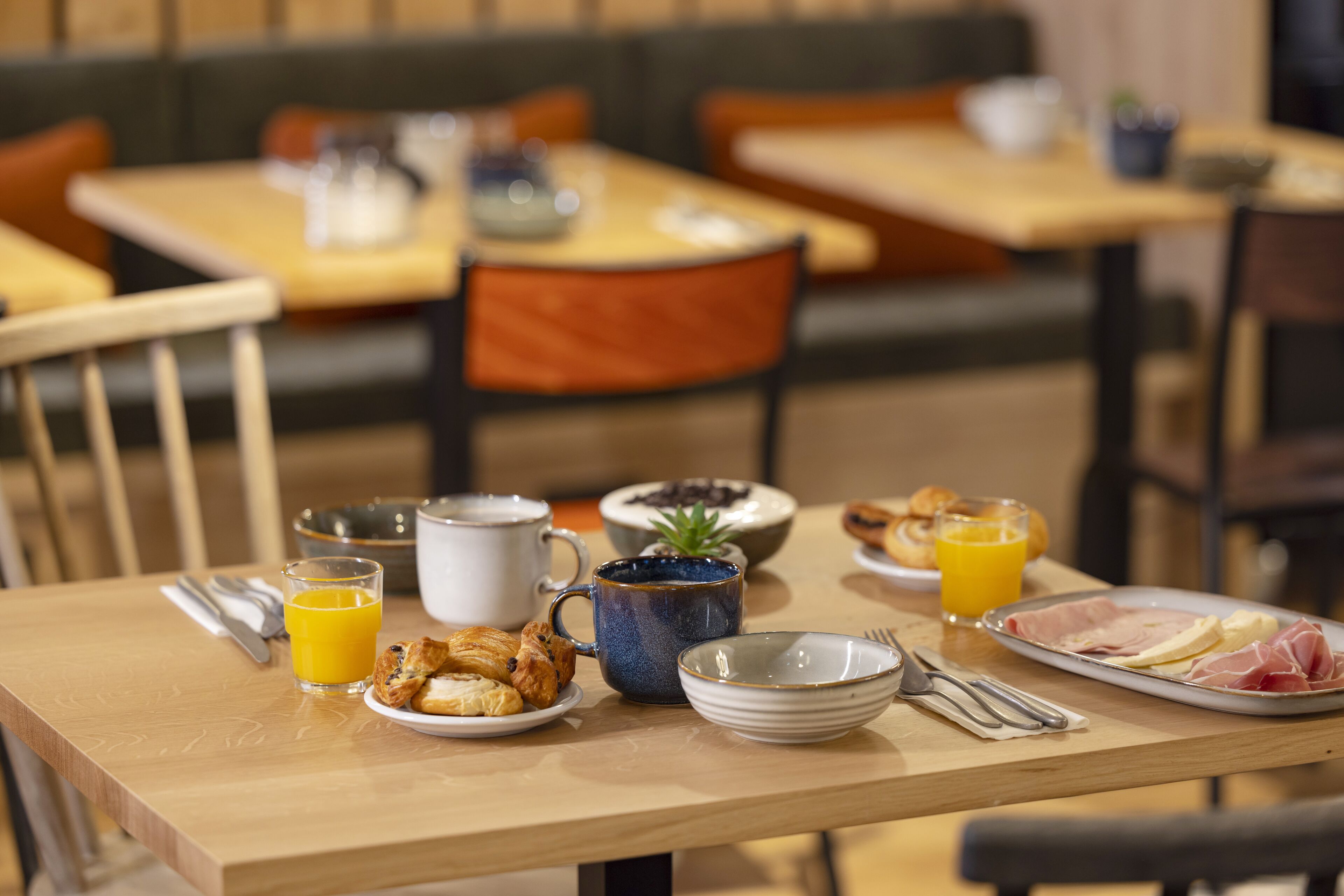 A breakfast table with plates of food, a coffee cup, a glass of orange juice, and a muffin.