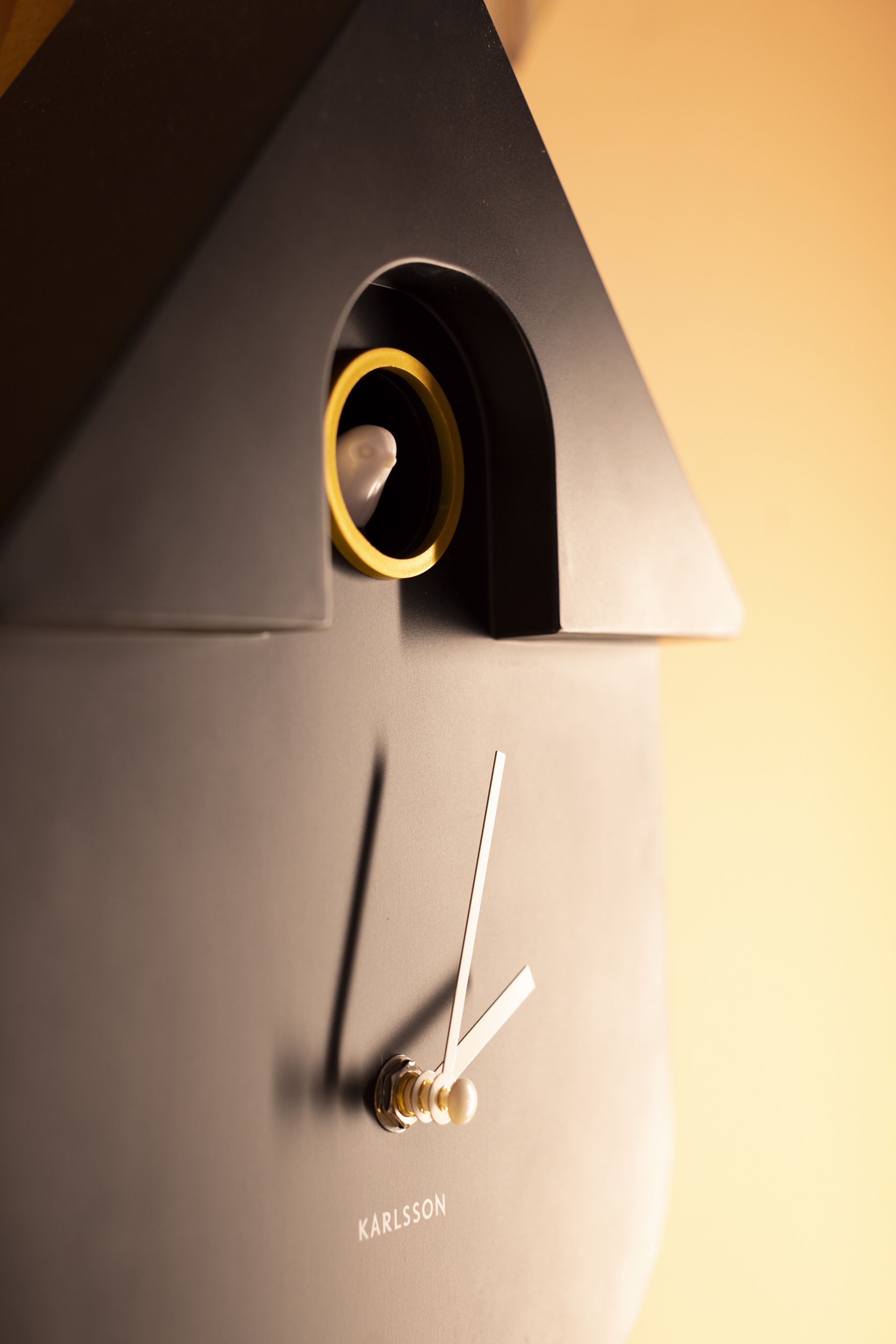 A clock with a minimalist design, featuring a black base and a gold-colored clock hand.