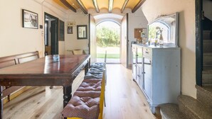 Un coin repas avec une table et des bancs en bois, une cuisine équipée de placards et un escalier.