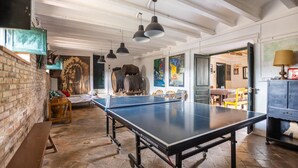 Une pièce spacieuse avec une table de ping-pong, des bancs en bois et un mur en briques.
