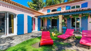 Une villa dotée d’un patio comprenant des fauteuils rouges, une sculpture de taureau jaune et une porte bleue.