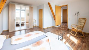 A spacious bedroom with a large bed, a rocking chair, and a wardrobe. - Wohnung in Battenberg nahe Winterberg Skigebiet (Battenberg)